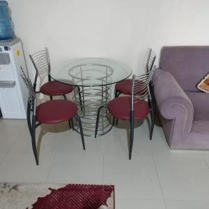 een glazen tafel met vier stoelen en een bank bij العين الهيلي مصباح بيت 8 in Al Ain
