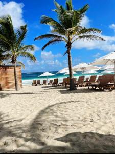 einen Strand mit Liegestühlen und Sonnenschirmen am Strand in der Unterkunft Hard Rock at Cana Pearl by Unwind Properties in Punta Cana