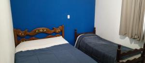 1 dormitorio con 2 camas y pared azul en casas temporada em Tiradentes do mazinho en Tiradentes