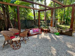 eine Terrasse mit Stühlen, einem Sofa und einer Schaukel in der Unterkunft Swiss House By Keri in Varkala