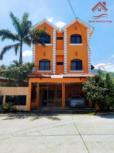 an orange building with a palm tree in front of it at Apart hotel la Trejo in San Pedro Sula