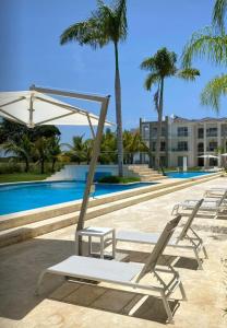 eine Gruppe von Liegestühlen neben einem Pool in der Unterkunft Hard Rock at Cana Pearl by Unwind Properties in Punta Cana