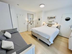 a white bedroom with a large bed and a bathroom at Ankerplatz in zentraler Lage in Warnemünde