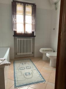 ein Bad mit einem WC, einem Fenster und einem Teppich in der Unterkunft Il Glicine in Bucine