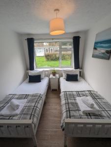 two beds in a room with a window at Pet Friendly 2 Bed Coastal Property - Millendreath, Looe in Looe