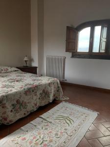 Schlafzimmer mit einem Bett, einem Fenster und einem Teppich in der Unterkunft Il Glicine in Bucine