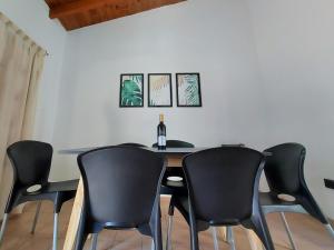 einen Esstisch mit schwarzen Stühlen und eine Flasche Wein in der Unterkunft Rincon Sanmartiniano in Mendoza