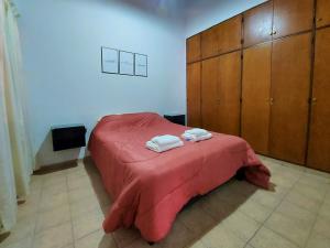 Schlafzimmer mit einem Bett mit einer roten Decke und Holzschränken in der Unterkunft Rincon Sanmartiniano in Mendoza
