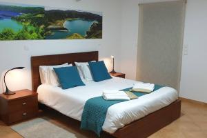 A Caminho da Ilha في بونتا ديلغادا: غرفة نوم بسرير كبير مع وسائد زرقاء
