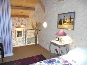 ein Schlafzimmer mit einem Bett und einem Tisch mit einer Lampe in der Unterkunft Le Colombier in Villeneuve-sur-Lot