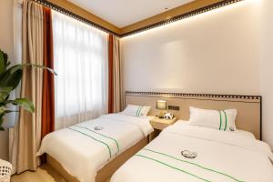 dwa łóżka w pokoju z oknem w obiekcie Xishu Garden Inn w mieście Chengdu