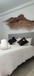 a white bed with pillows and a painting on the wall at La Fortaleza House MOGAN in Mogán