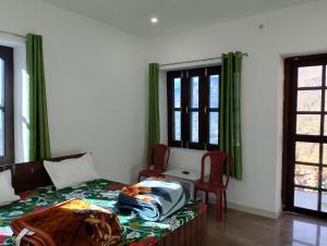 a bedroom with a bed and two chairs and windows at Birthi Waterfall Homestay in Girgaon