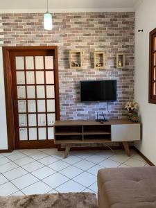 a living room with a television on a brick wall at Casa prox á praia e aeroporto in Florianópolis