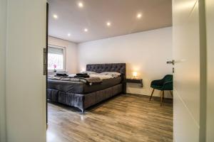 a bedroom with a bed and a green chair at Sweet Six, Sauna, Balkon, Netflix, Boxspringbetten, hochwertiges Bad in Zell an der Mosel