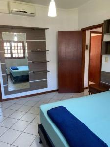 a bedroom with a blue bed and a mirror at Casa prox á praia e aeroporto in Florianópolis