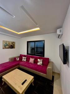sala de estar con sofá rojo y TV en Studio de luxe, en La Soukra
