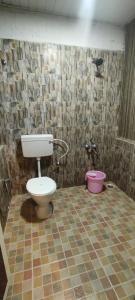 a bathroom with a toilet and a pink bucket at Wild tusker in Masinagudi