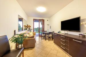 sala de estar con TV de pantalla plana y comedor en Rosa Flat - with Pool, en Polpenazze del Garda
