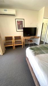een hotelkamer met een bed, een bureau en een televisie bij 408 Abundant Abode Cbdpad Best Location in Perth