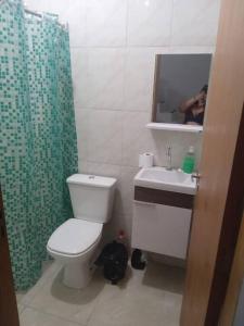 a bathroom with a toilet and a sink and a mirror at Casa Vale da Paz - Massaguaçu. in Caraguatatuba