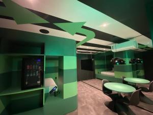 a room with green walls and tables and a tv at Andar de Cima Suítes in Sao Paulo