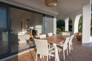 una mesa de madera y sillas en un patio con chimenea en Villa Eloah - Magnifique villa portugaise rénovée vue mer, en Carvoeiro