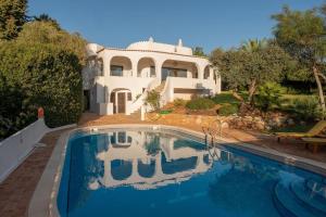 una casa con piscina frente a ella en Villa Eloah - Magnifique villa portugaise rénovée vue mer, en Carvoeiro