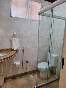 a bathroom with a toilet and a glass shower stall at Casa com ar condicionado in Lauro de Freitas