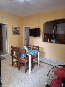 ein Esszimmer mit einem Tisch, Stühlen und einem TV in der Unterkunft Casa com ar condicionado in Lauro de Freitas