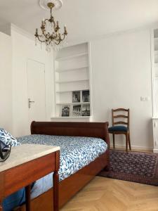 a bedroom with a bed and a chair and a chandelier at Apartment quartier St Louis - 10 mins walking Château Versailles in Versailles