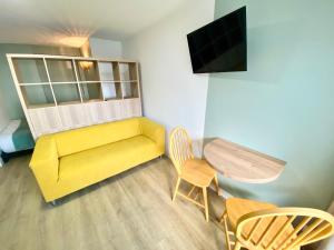 salon z żółtą kanapą i stołem w obiekcie L'Escale Appartements et Suites en bord de Mer w Hawrze