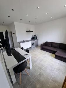 uma sala de estar com uma secretária e um sofá em Appartement neuf 36m2 climatisé em Chamaret