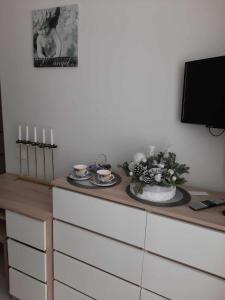 a dresser with a table with two plates and candles at Upės apartamentai in Biržai