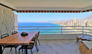 een balkon met een houten tafel en uitzicht op de oceaan bij Magnificent and Luxury apartment at 22 floor and on the first line at Levante Beach beach in Benidorm