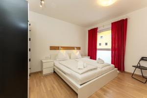 Schlafzimmer mit einem großen weißen Bett und roten Vorhängen in der Unterkunft Appartement Göbel by Schladming Appartements in Haus im Ennstal