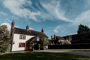 a white house with red windows and a driveway at Oak Farm Hotel in Cannock