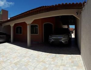 a car parked in a garage next to a house at Casa confortável com 4 suítes para até 20 pessoas. in Itanhaém