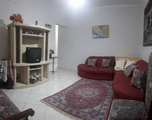 a living room with a red couch and a tv at Casa confortável com 4 suítes para até 20 pessoas. in Itanhaém