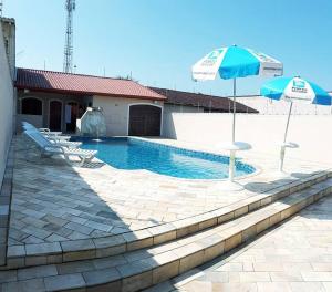 a swimming pool with two chairs and an umbrella at Casa confortável com 4 suítes para até 20 pessoas. in Itanhaém