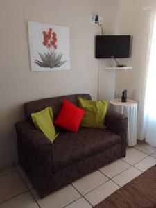 a brown couch with four colorful pillows on it at Raiden's Home in Saldanha