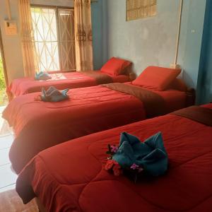 een groep van vier bedden in een kamer met rode lakens bij Phonephithak Guesthouse in Pakbeng