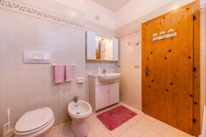 La salle de bains est pourvue de toilettes, d'un lavabo et d'une porte en bois. dans l'établissement Ciasa Piz appartamento Aloch, à Pozza di Fassa