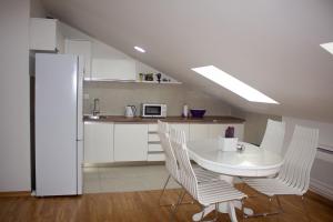 a white kitchen with a white table and chairs at Apartman Mazić Nikšić in Nikšić +10 photos