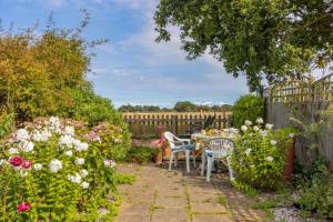 a garden with a table and chairs and flowers at 4 Church Cottages in Reydon