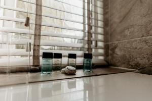 a bathroom counter with three bottles of soap and a window at Oak Farm Hotel in Cannock