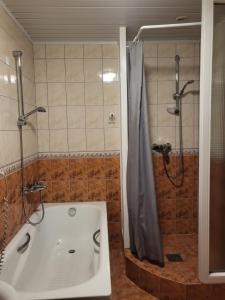 uma casa de banho com um chuveiro e uma banheira branca em Apartamentai Taikos 10-36 Nida em Nida