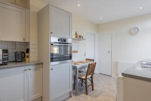 a kitchen with white cabinets and a table with a dining room at Albany Cottage in Southwold
