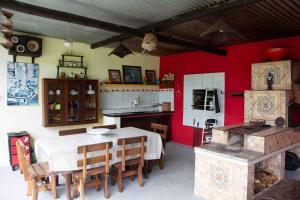 Zimmer mit einem Tisch und einer Küche mit roten Wänden in der Unterkunft Chácara à beira do lago em São Luiz do Paraítinga in Natividade da Serra