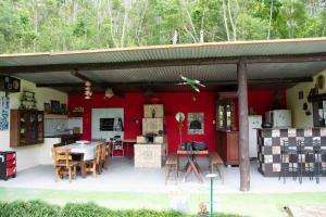 eine Küche mit einer roten Wand sowie einem Tisch und Stühlen in der Unterkunft Chácara à beira do lago em São Luiz do Paraítinga in Natividade da Serra